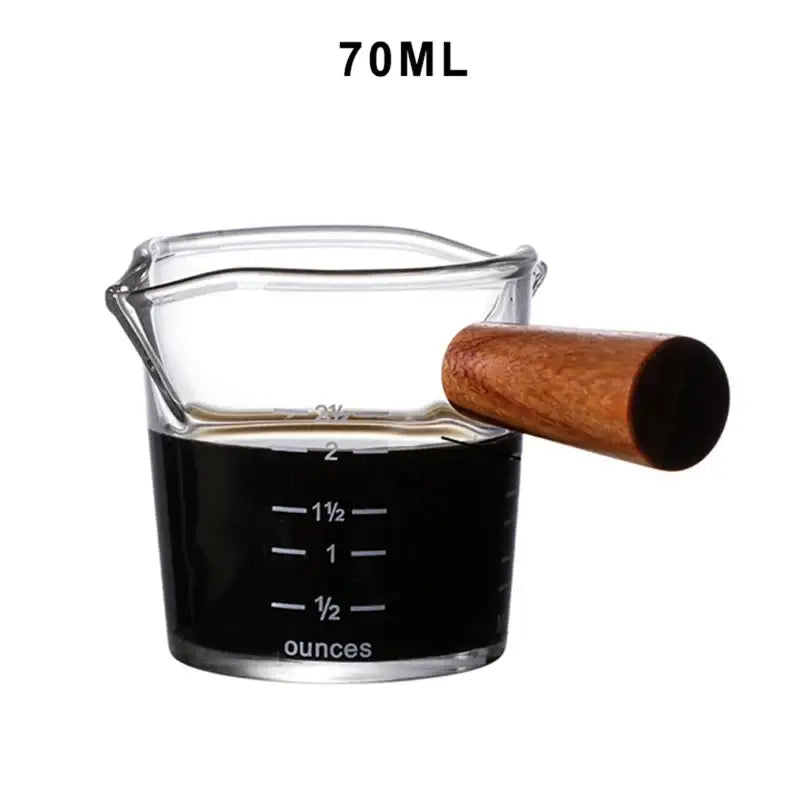 A clear glass espresso milk jug with measurement lines and a wooden handle heat resistant milk jug 70ml capacity