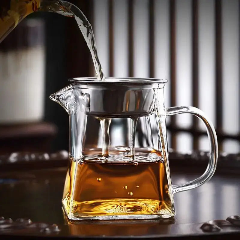 Clear glass teapot with stainless steel infuser filled with amber tea for heat resistant glass fair cup kung fu tea set
