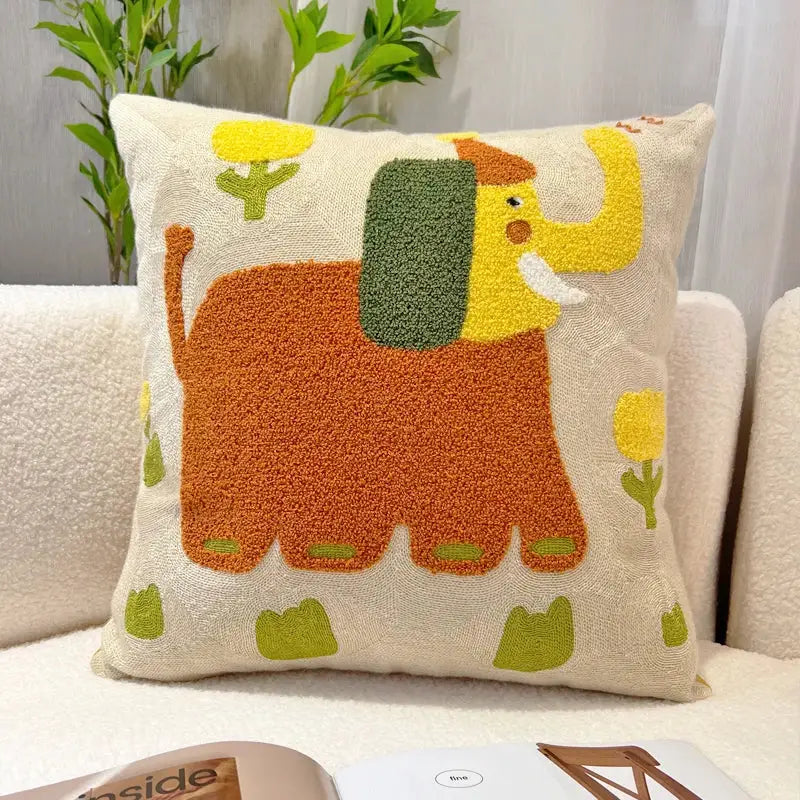 Cream-colored throw pillow with playful orange embroidered elephant featuring yellow trunk and green ears decorbites cartoon oil design