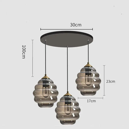 Modern three-light pendant light with smoked honeycomb amber blue and gray glass shades and brass accents for kitchen decorbites colorful glass