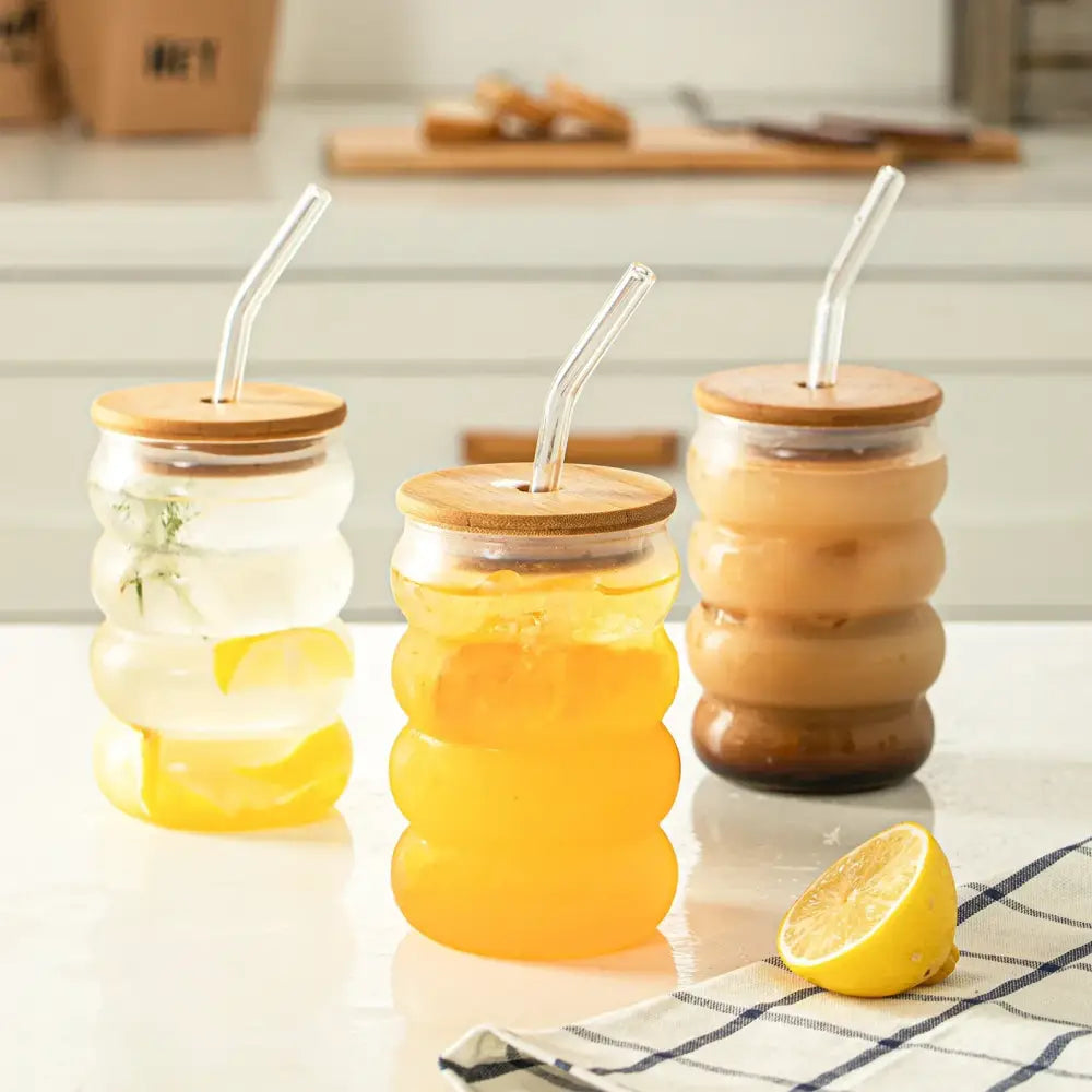 Three honeycomb creative glass tumblers with bamboo lids and colorful beverages in a decorbites glass cup set