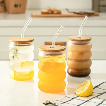 Three honeycomb creative glass tumblers with bamboo lids and colorful beverages in a decorbites glass cup set