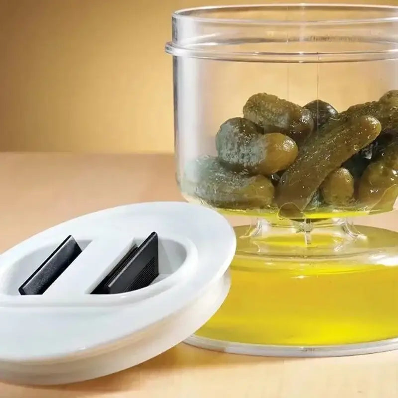 Clear plastic hourglass pickle and olive dispenser jar with white lid and black magnetic strips filled with green pickles