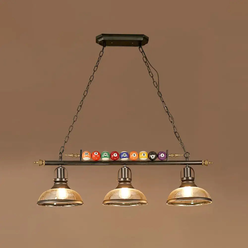 Industrial style three-light pool table lamp with black metal frame brass accents amber glass shades and billiard ball deco