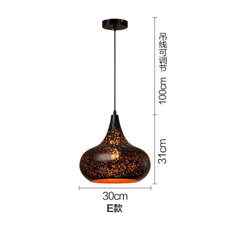A sleek black and gold etched wrought iron chandelier with a speckled surface and orange glow for dining room decor