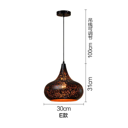 A sleek black and gold etched wrought iron chandelier with a speckled surface and orange glow for dining room decor