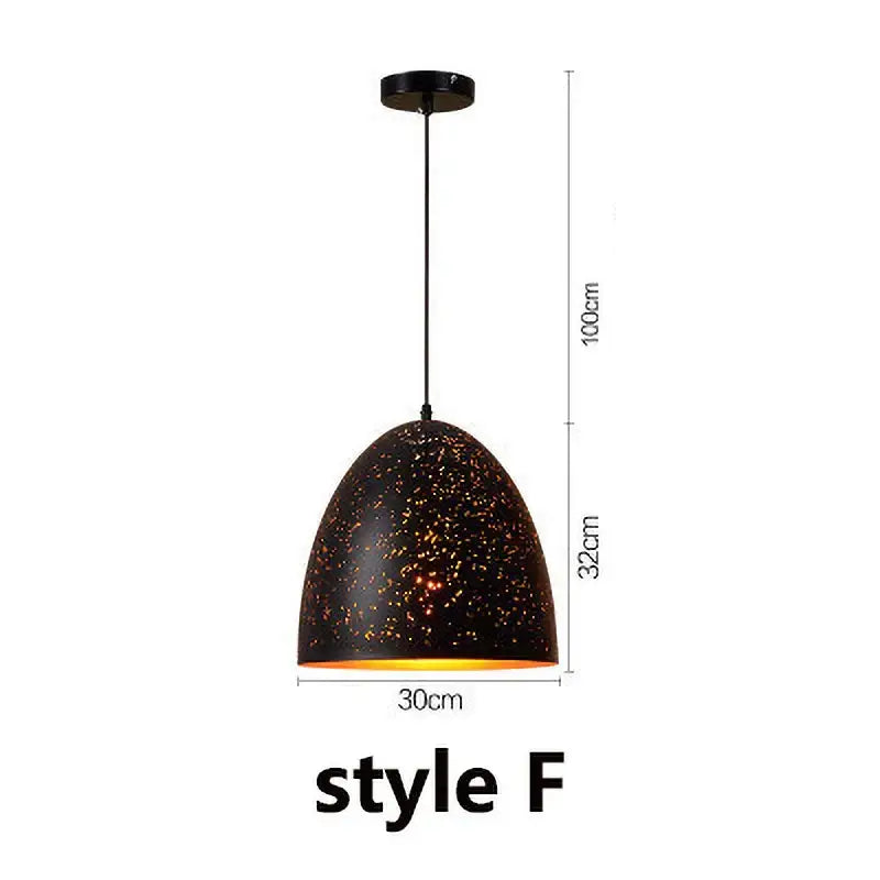 Industrial black and gold etched wrought iron chandelier with black speckled pendant light and warm glowing interior