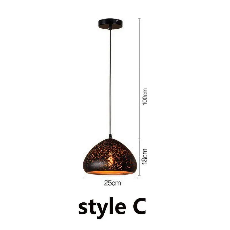 A sleek dark bronze pendant light with speckled texture and amber glow in industrial black and gold etched wrought iron chandelier