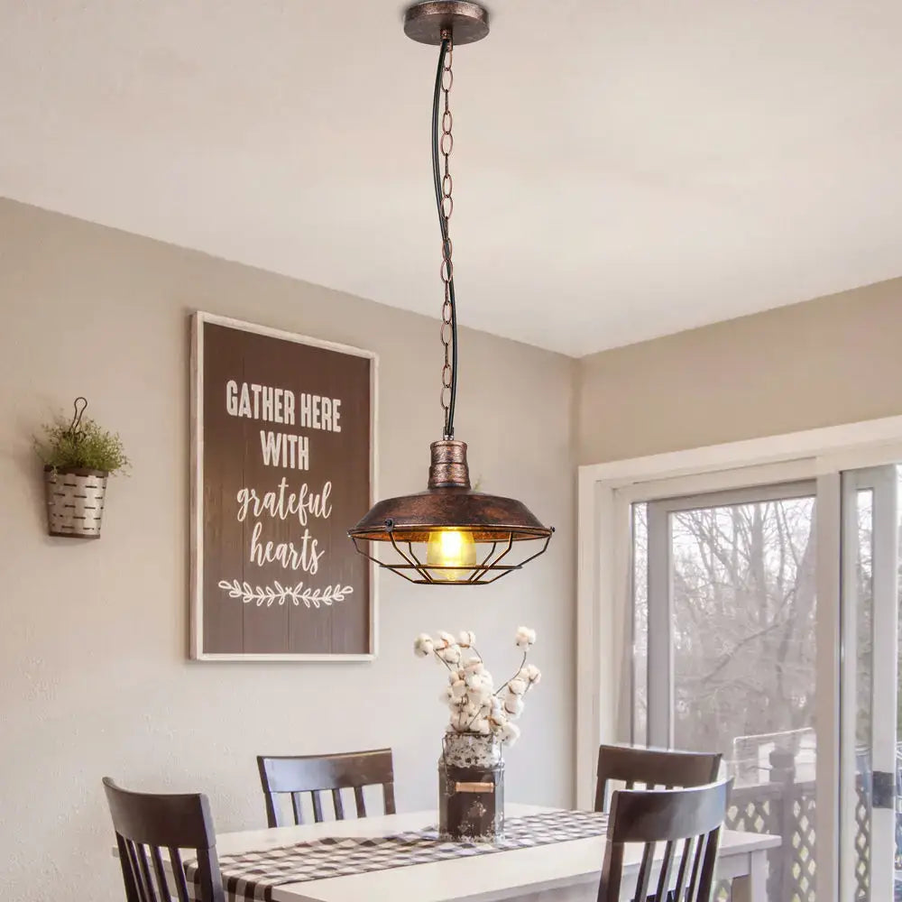 Industrial black and copper iron pendant lights featuring a warm glowing bulb in a dark bronze metal cage for dining room decorbites iron pendant