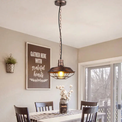 Industrial black and copper iron pendant lights featuring a warm glowing bulb in a dark bronze metal cage for dining room decorbites iron pendant