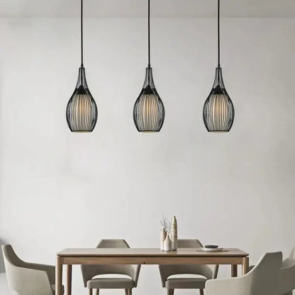 Three black iron cage pendant lights with modern teardrop design from decorbites hang above dining table