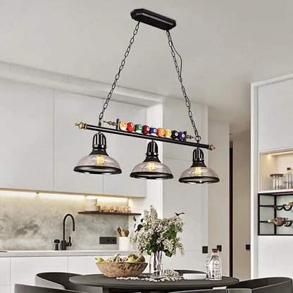 DecorBites™ rustic black island pendant light kit with clear glass shades and a bar holding colorful billiard balls
