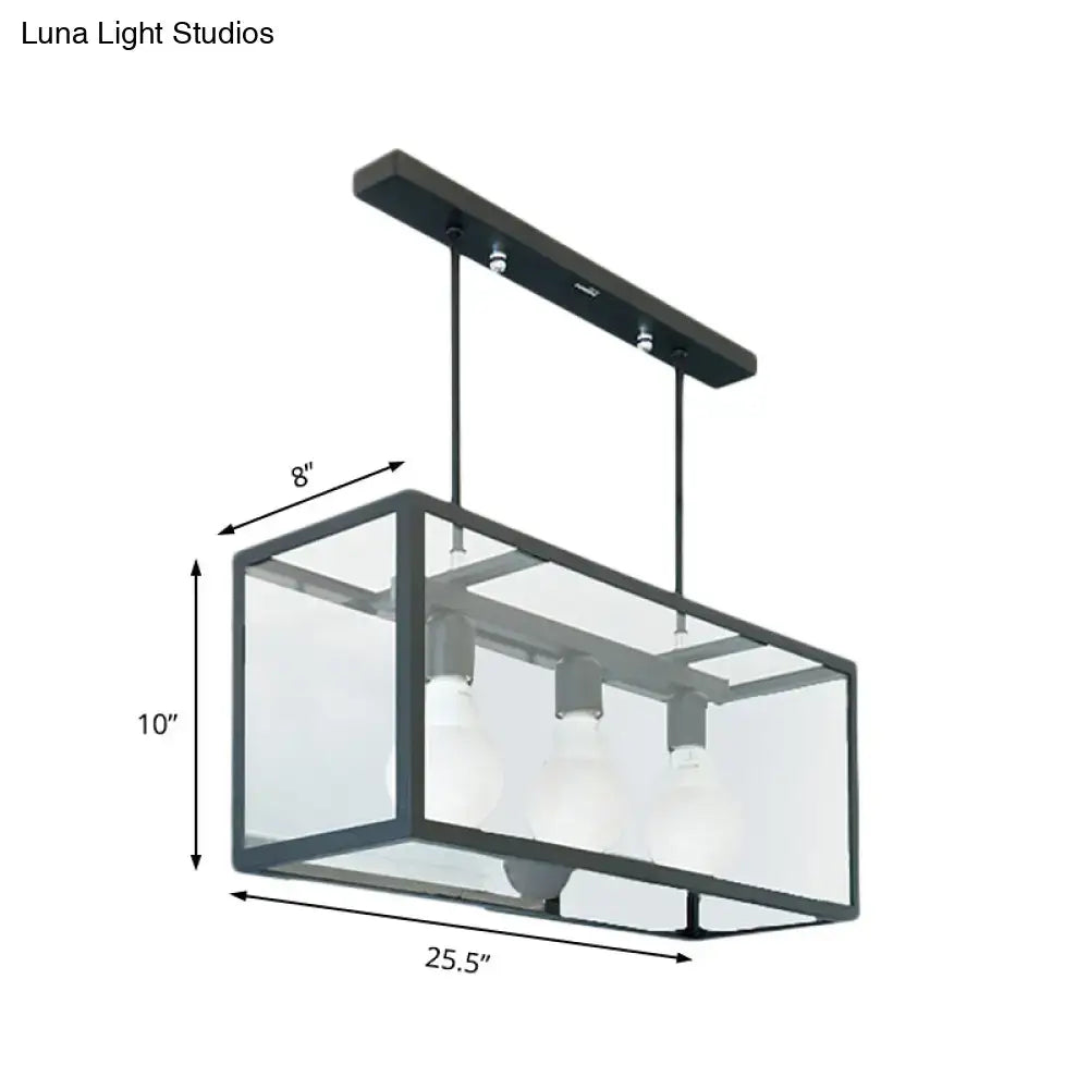 Black metal rectangular pendant light with clear glass panels and three exposed bulbs for industrial kitchen island use