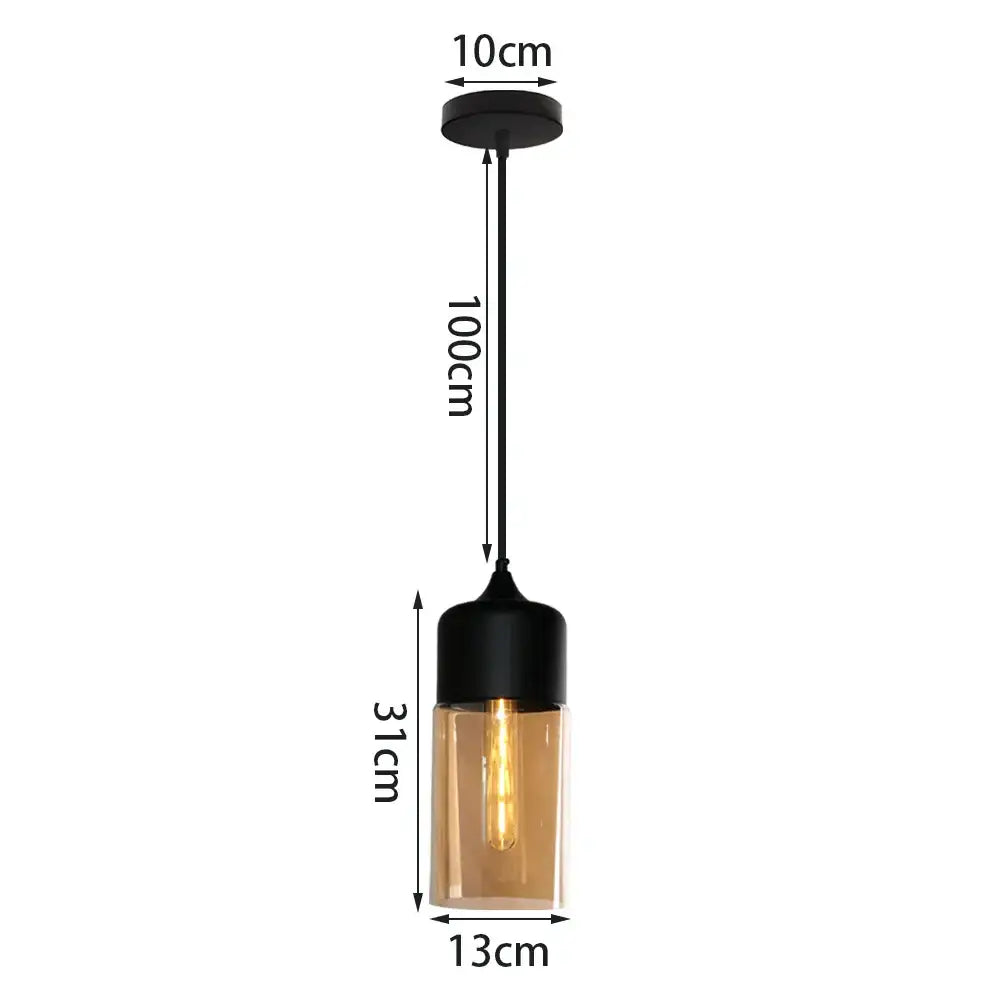 Black metal pendant light with cylindrical amber glass shade featuring exposed filament bulb for kitchen decor