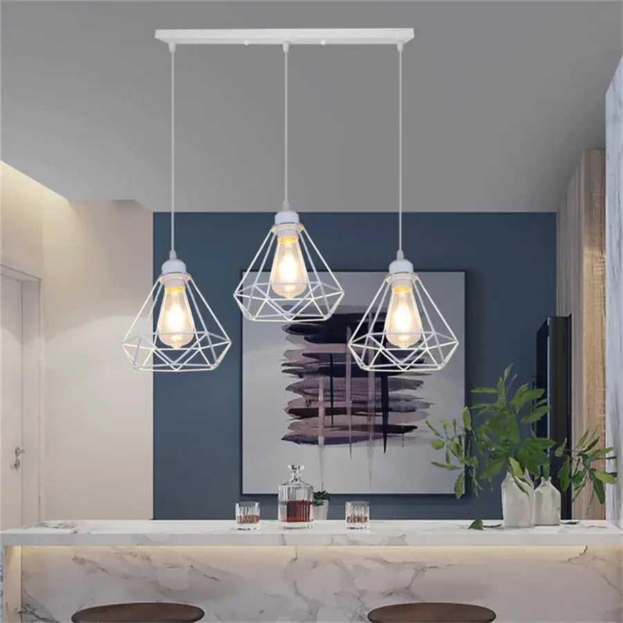Three white pendant lights with diamond cage wrought iron design hang from a matching ceiling bar for kitchen use