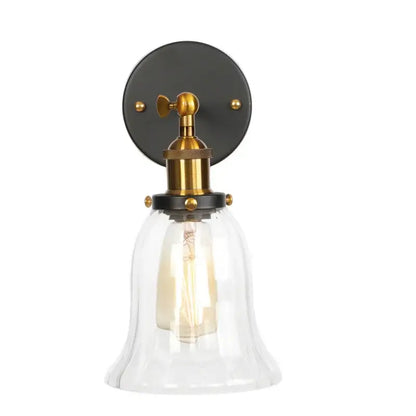 Industrial brass and clear glass wall sconce with a clear glass bell-shaped shade and black metal mounting plate for bedroom decor
