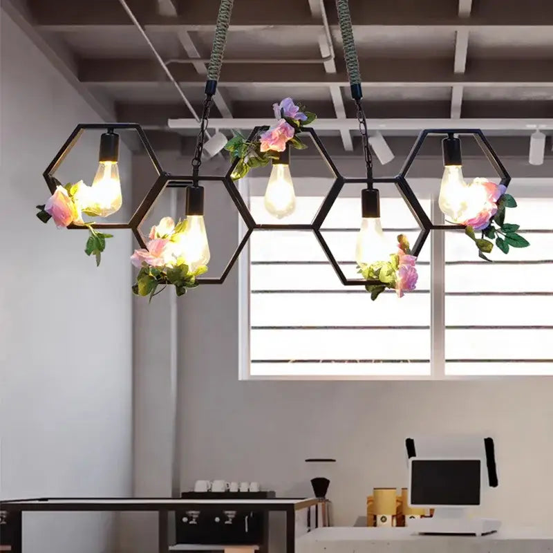 Industrial brass hexagonal pendant light with black frame, exposed filament bulbs, and pink floral accents for dining decorbites industrial style
