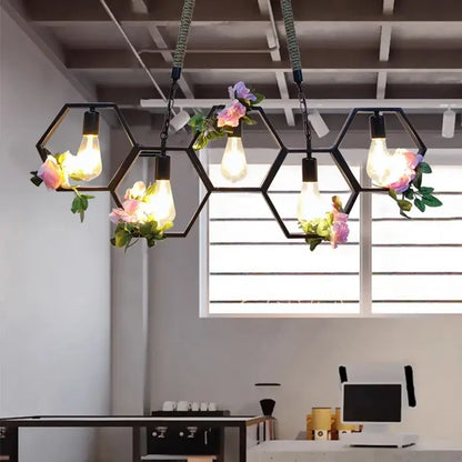 Industrial brass hexagonal pendant light with black frame, exposed filament bulbs, and pink floral accents for dining decorbites industrial style