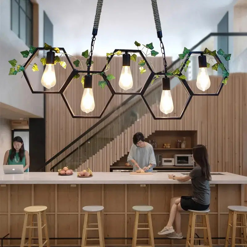 Black hexagonal industrial style pendant light with brass accents and green ivy for bar and restaurant dining decorbites industrial style
