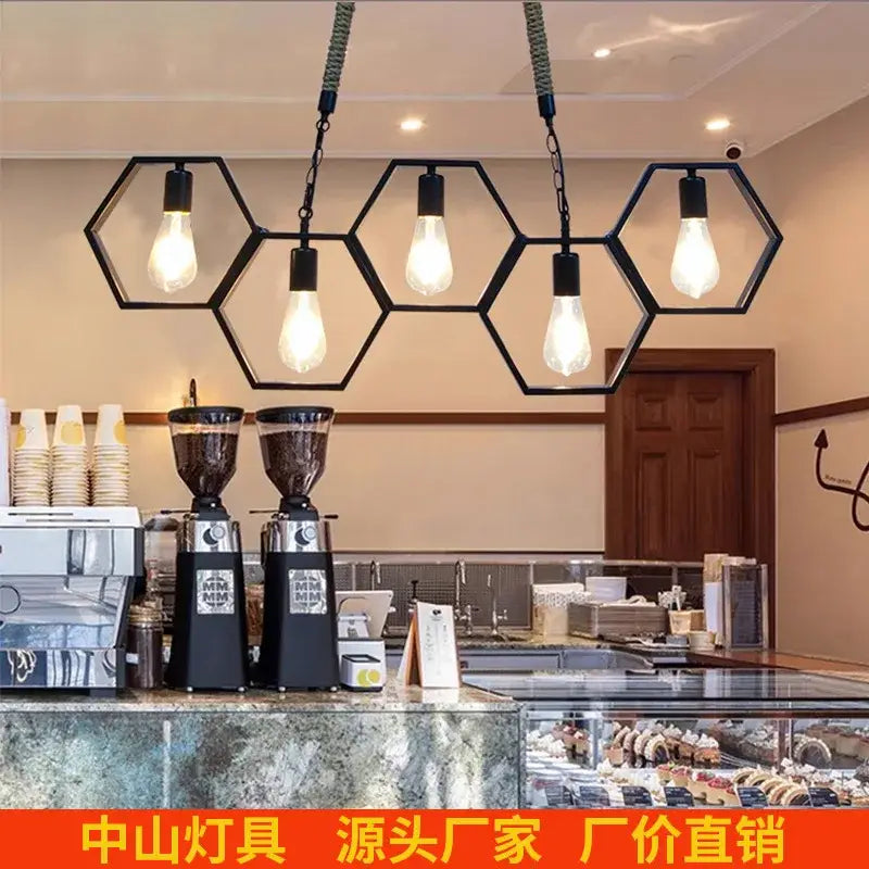 Black brass hexagonal industrial style pendant light with exposed filament bulbs hanging above coffee shop counter