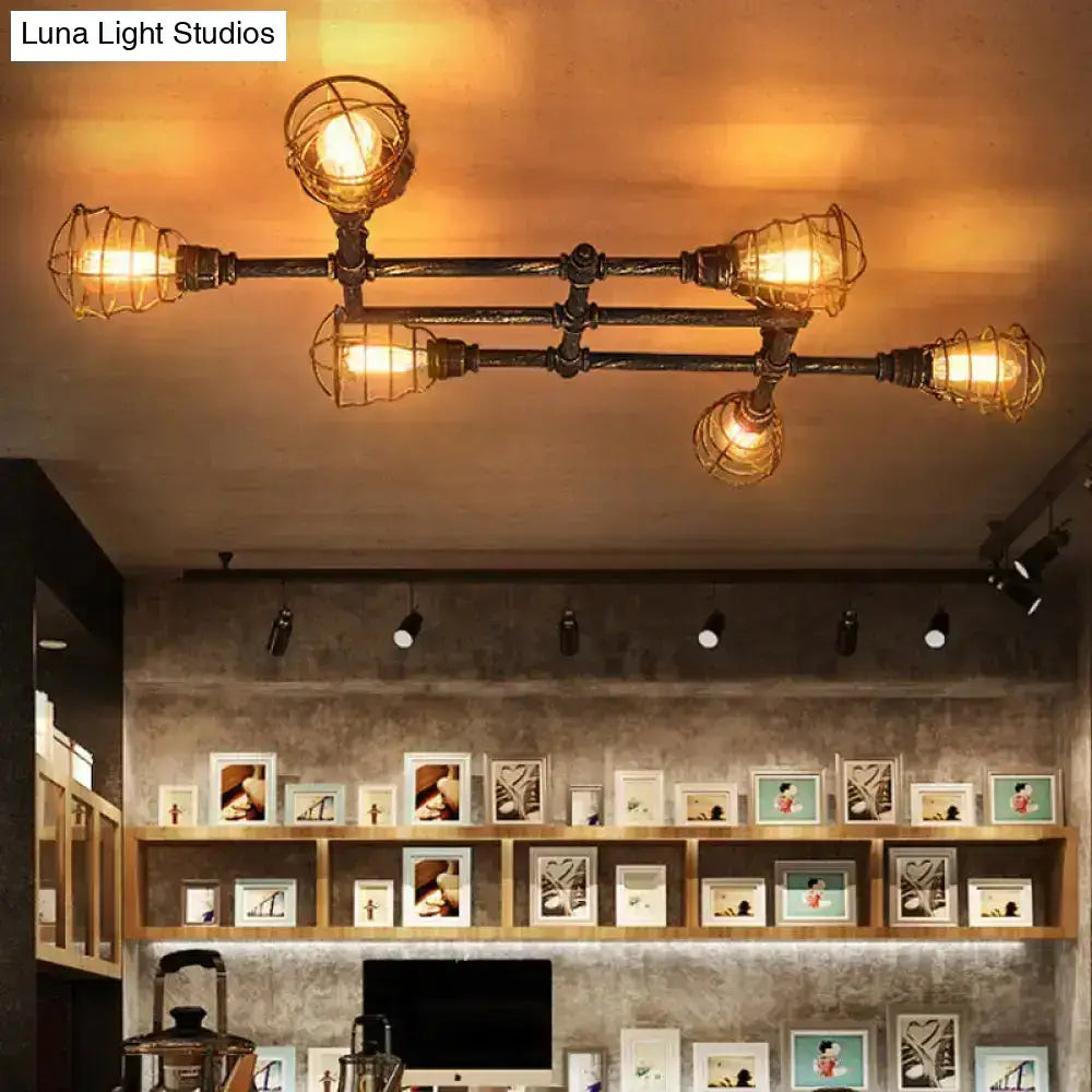 Industrial brass intersecting piping ceiling light with four exposed bulbs in wire mesh cages for dining room use