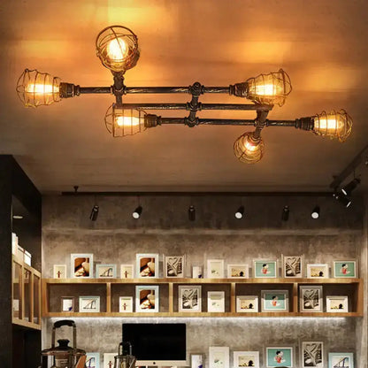 Industrial brass intersecting piping ceiling light with four exposed bulbs encased in wire mesh cages for dining room