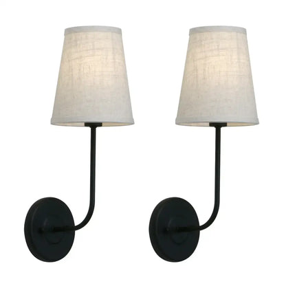 Pair of black wrought iron wall lamps with off-white linen shades in an industrial brass wall lamp set for bedroom reading