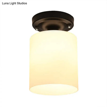 Warm-toned cylindrical industrial milky glass shade on a black semi flush light with dark bronze ceiling mount for corridor