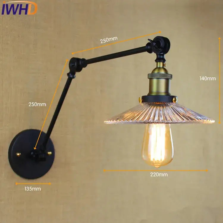 Industrial chrome glass swing arm wall lamp with black articulated arm, brass accents, faceted glass shade, and exposed edison bulb