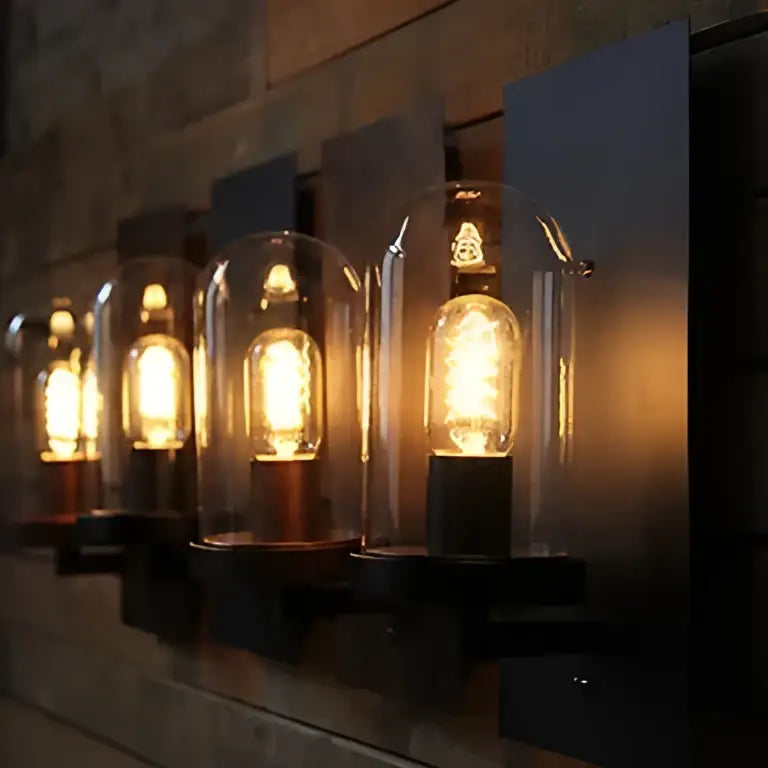 Warmly glowing industrial edison vintage wall sconce with clear glass domes on black metal decorbites fixtures