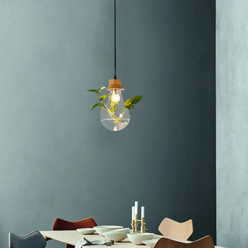 Industrial glass and wood pendant light kit with exposed bulb and green plant stems for dining room illumination