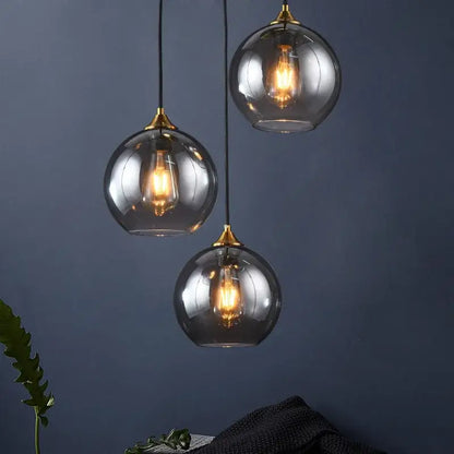 Three spherical glass pendant lights with brass accents and warm filament bulbs for kitchen dining room decorbites industrial glass pendant