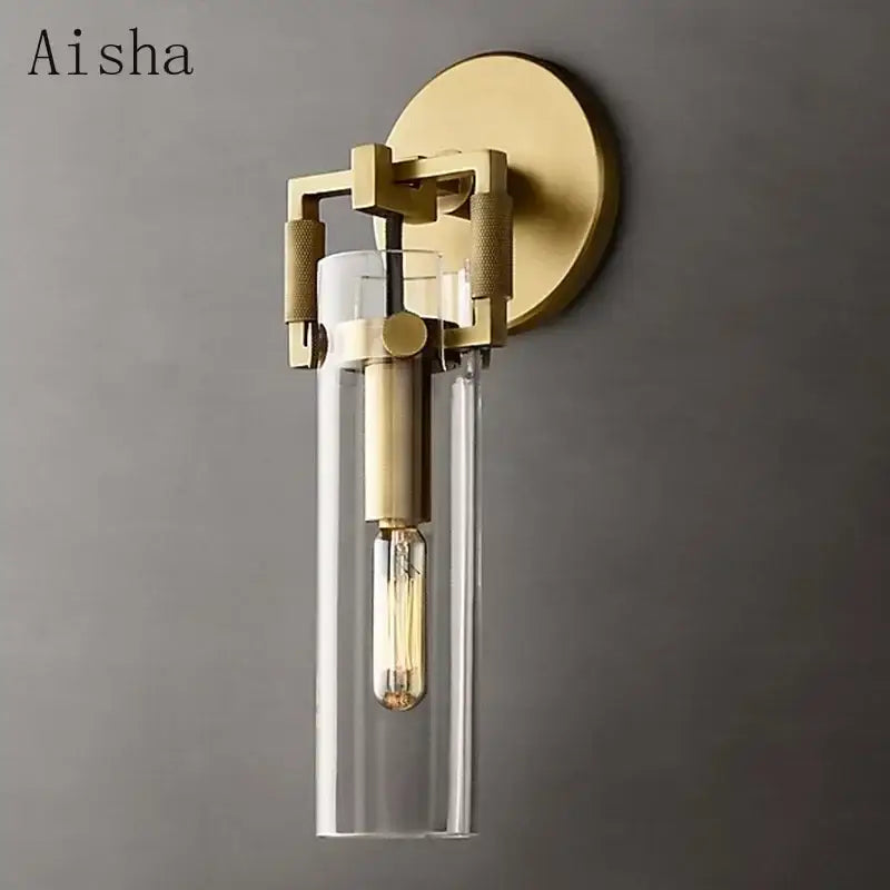Gold-toned industrial glass wall lamp decorbites with clear cylindrical shade and exposed filament bulb for bedroom sconce