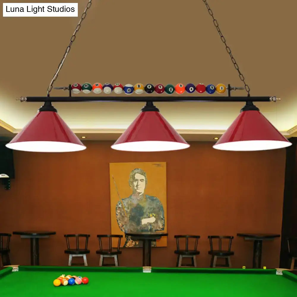 Red conical metal billiard lamp with black fixtures and colorful balls hanging above a country club island pool table