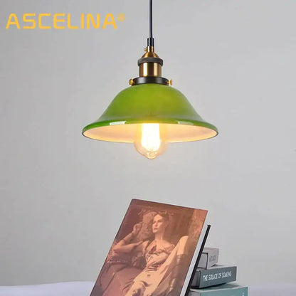 Industrial green glass pendant light with brass accents and visible filament bulb for dining room lighting