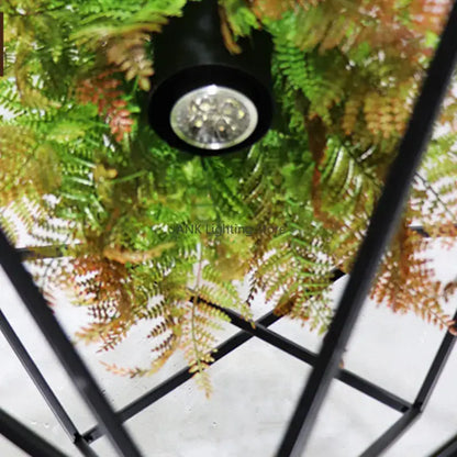 Black cylindrical led spotlight with clear lens mounted above green and brown ferns in decorbites industrial greenery chandelier