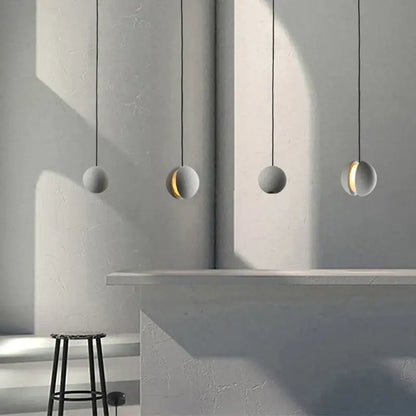 Four minimalist spherical pendant lamps with matte gray cement and gold inner glow by decorbites cement chandelier