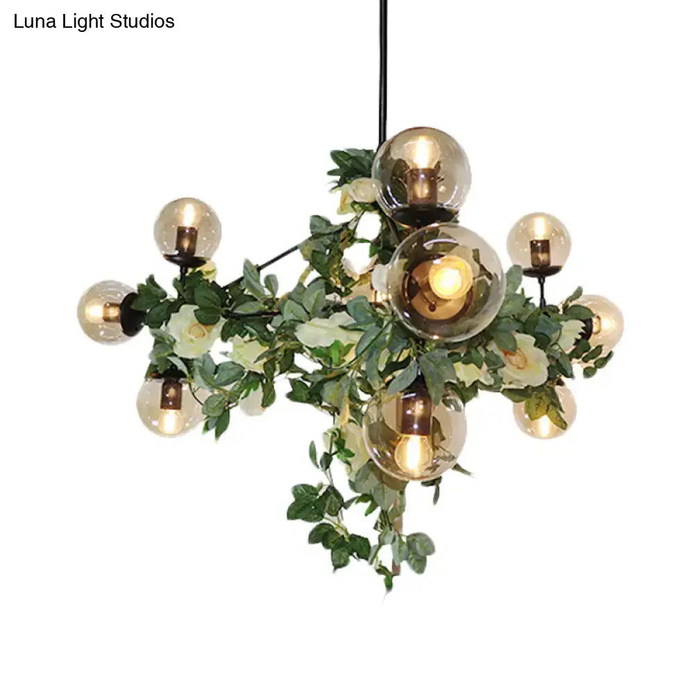 A decorbites™ industrial globe island pendant in black with smoke gray glass bulbs surrounded by green vines and flowers