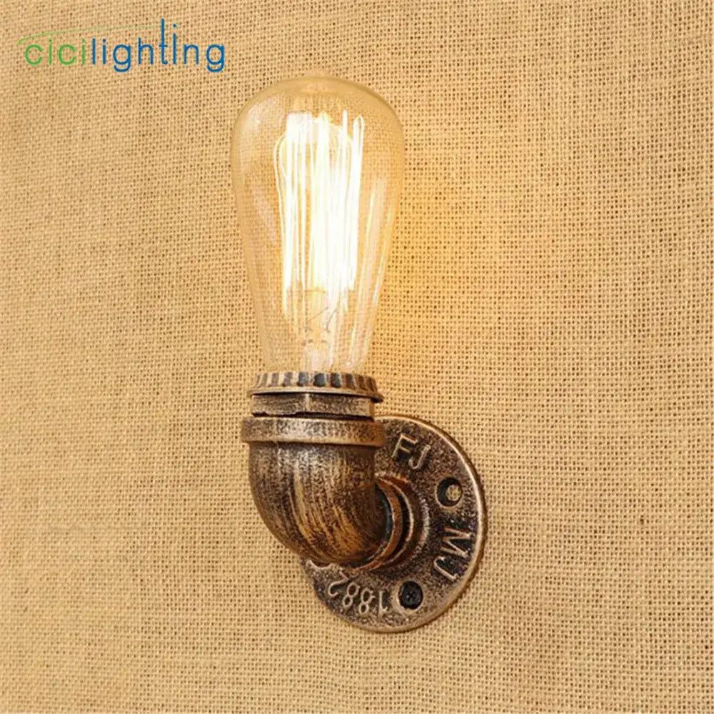 Industrial steampunk loft pipe wall lamp with black and aged brass finish featuring an exposed edison bulb for decorbites steampunk loft decor