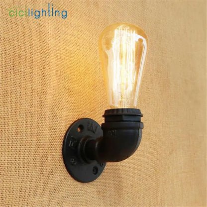 Industrial steampunk loft pipe wall lamp with black pipe and aged brass finish featuring a warm amber filament bulb