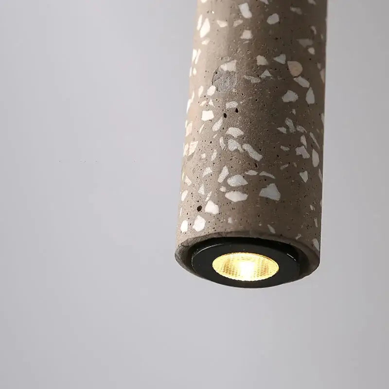 A cylindrical terrazzo pendant lamp with speckled gray white concrete finish and warm led bulb for kitchen decorbites industrial stone led