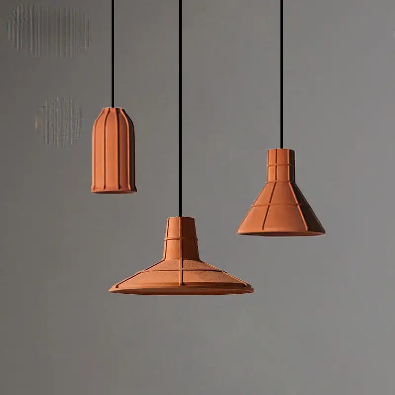Three terracotta cement pendant lamps with geometric segmented design hanging from black cords for dining room decorbites cement pendant