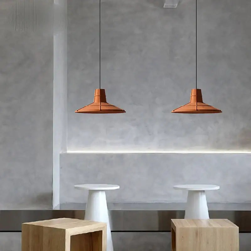 Two terracotta cement pendant lamps with geometric design hang in a dining room decorbites cement pendant light