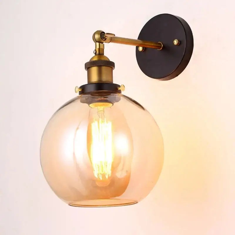 Industrial vintage black and brass wall sconce with warm amber glass globe and decorbites industrial vintage loft appeal