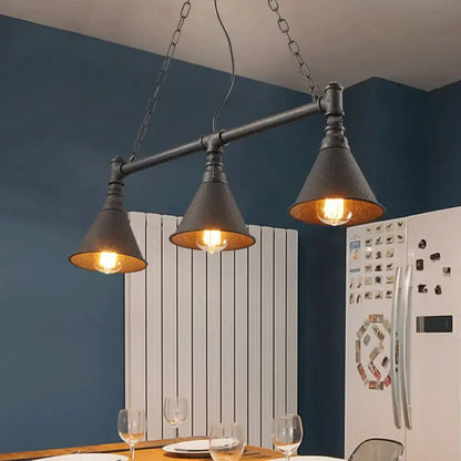 Industrial black metal pendant light with three conical shades and exposed bulbs for rust-coloured island lighting