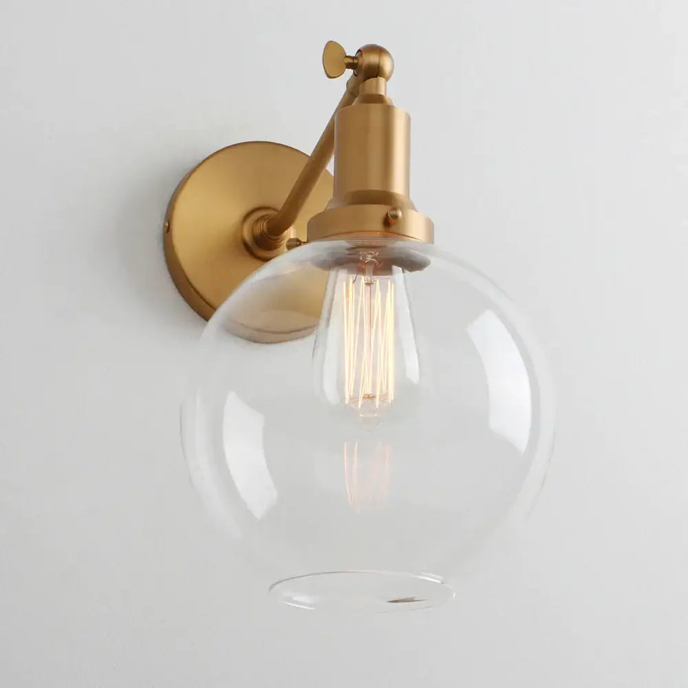 Gold-finished industrial vintage wall sconce with clear glass globe and exposed filament bulb for decorbites bedroom lighting