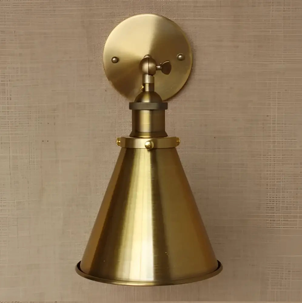 Industrial vintage brass wall sconce with a conical shade, circular backplate, and adjustable arm for bedroom lighting