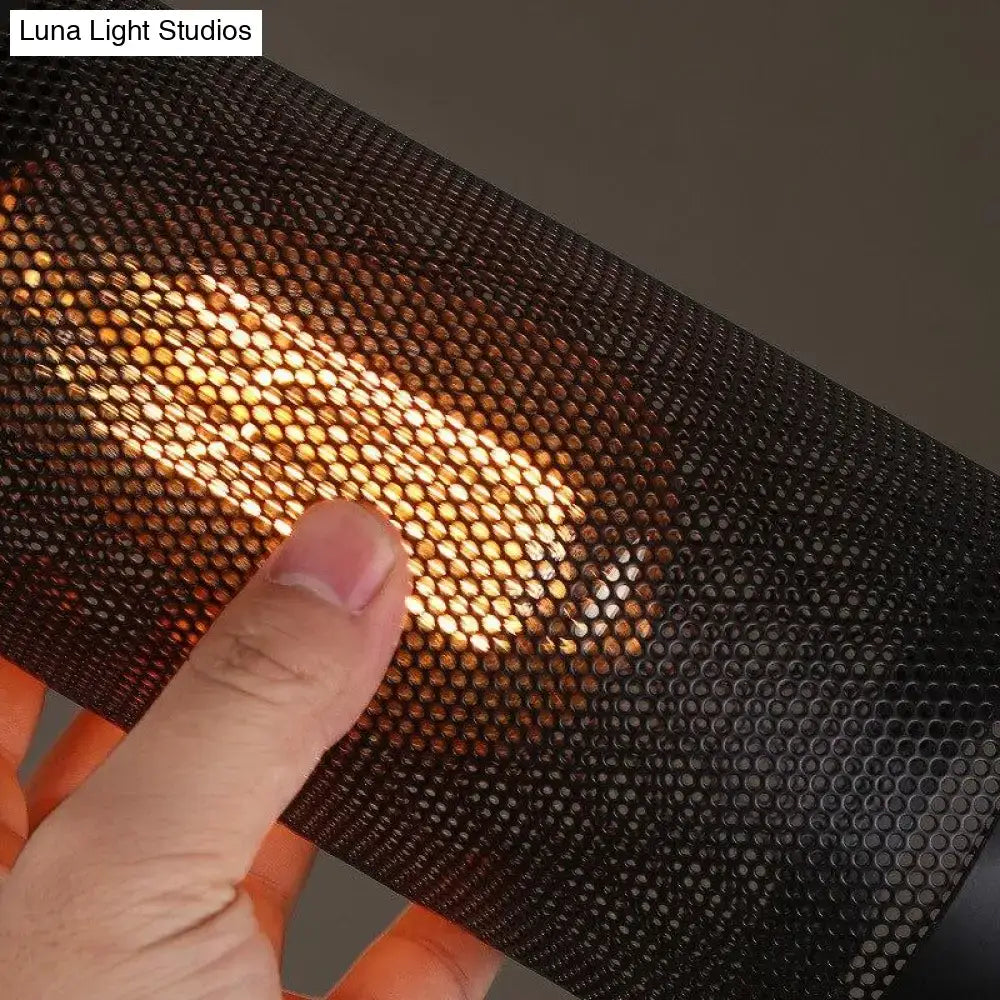 Black perforated mesh panel with honeycomb pattern illuminated by warm golden light in vintage metal pendant light