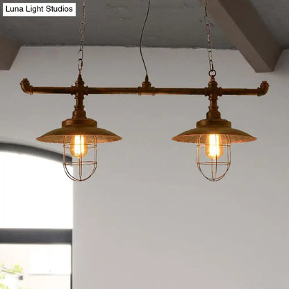 Industrial-style brass pendant light with two exposed filament bulbs in weathered copper wire cages suspended by chain cord length