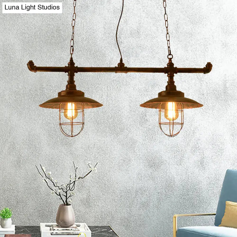 Industrial-style brass pendant light with two exposed filament bulbs in wire cages suspended by chain with weathered copper pipe design